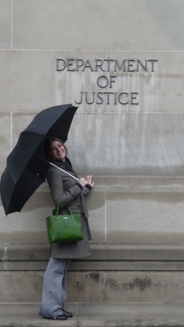 lady standing holding umbrella next to department of justice sign
